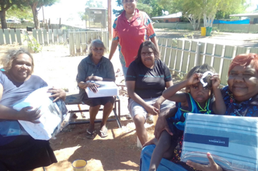 A group of smiling Indigenous women from a remote community with donations of Sheridan bedding